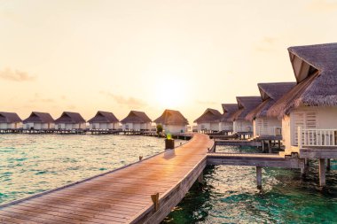 Su bungal ile Maldivler Adası üzerinde güzel tropikal günbatımı