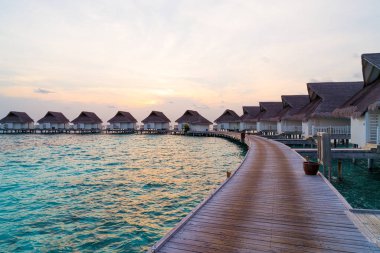Su bungal ile Maldivler Adası üzerinde güzel tropikal günbatımı