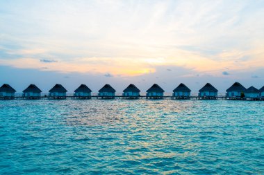 Su bungal ile Maldivler Adası üzerinde güzel tropikal günbatımı