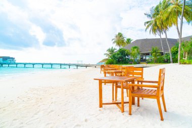 Maldiv 'de deniz manzaralı arka plan ile sahilde ahşap masa ve sandalye