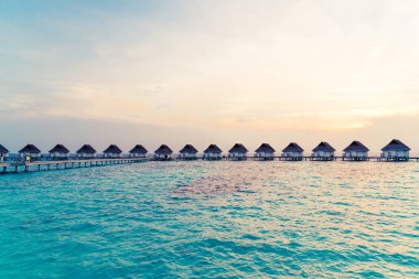 Su bungal ile Maldivler Adası üzerinde güzel tropikal günbatımı
