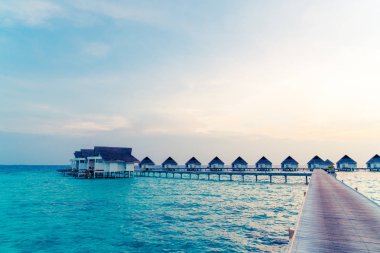 Su bungal ile Maldivler Adası üzerinde güzel tropikal günbatımı