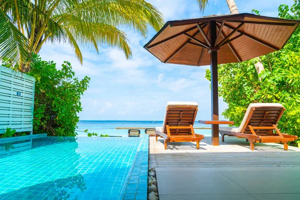 Maldivler yüzme havuzu ve deniz arka plan ile plaj sandalyesi