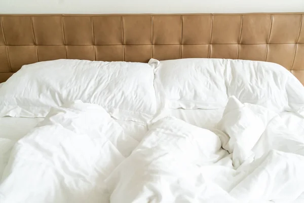 Cama desordenada con almohada blanca y manta en la cama — Foto de Stock