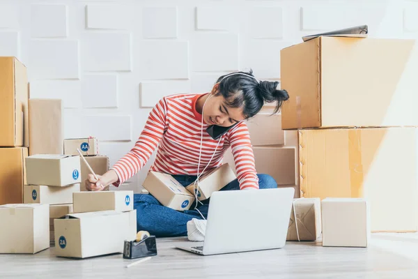Asya kadın iş sahibi çalışan evde ambalaj kutusu ile w
