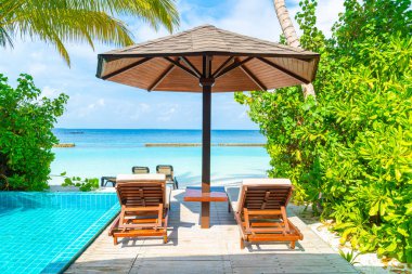 Maldivler yüzme havuzu ve deniz arka plan ile plaj sandalyesi