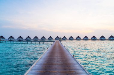 Su bungal ile Maldivler Adası üzerinde güzel tropikal günbatımı