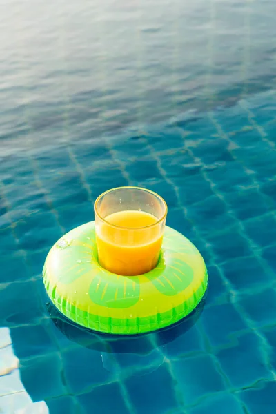 Orange juice glass with swim ring at outdoor swimming pool — Stock Photo, Image