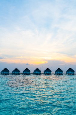 Su bungal ile Maldivler Adası üzerinde güzel tropikal günbatımı