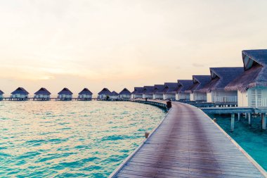 Su bungal ile Maldivler Adası üzerinde güzel tropikal günbatımı