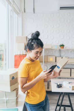 Asya kadın iş sahibi çalışan evde ambalaj kutusu ile w