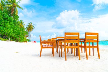 Maldiv 'de deniz manzaralı arka plan ile sahilde ahşap masa ve sandalye