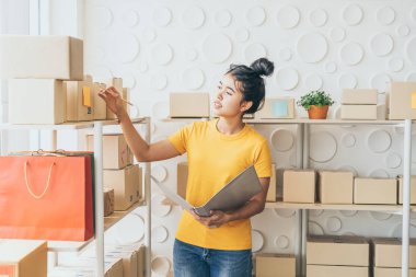  Genç Asyalı kadın ambar stok raf üzerinde mal kontrol