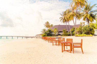 Maldiv 'de deniz manzaralı arka plan ile sahilde ahşap masa ve sandalye