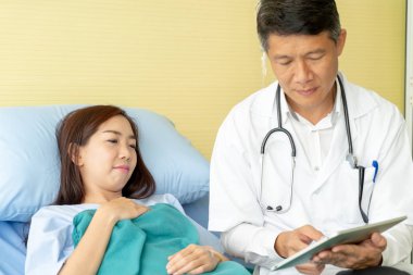 Hastane yatağı üzerinde oturan ve ile tartışırken Asya kıdemli doktor 