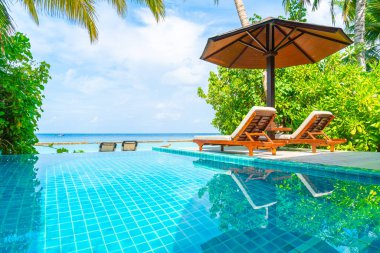 Maldivler yüzme havuzu ve deniz arka plan ile plaj sandalyesi