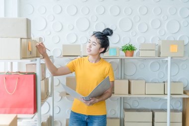  Genç Asyalı kadın ambar stok raf üzerinde mal kontrol