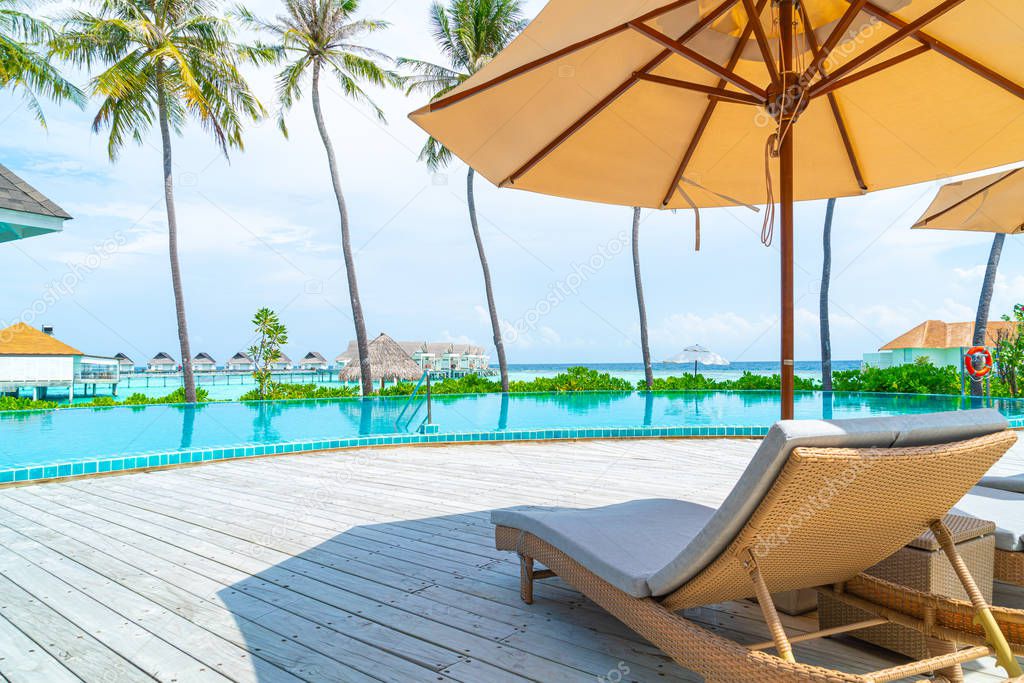 Umbrella and chair around swimming pool in resort hotel 