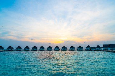 Su bungal ile Maldivler Adası üzerinde güzel tropikal günbatımı