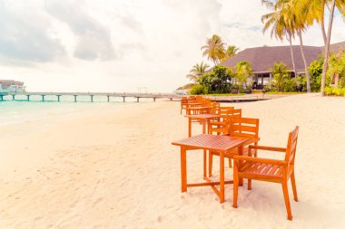 Maldiv 'de deniz manzaralı arka plan ile sahilde ahşap masa ve sandalye
