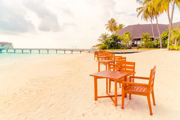 Maldiv 'de deniz manzaralı arka plan ile sahilde ahşap masa ve sandalye
