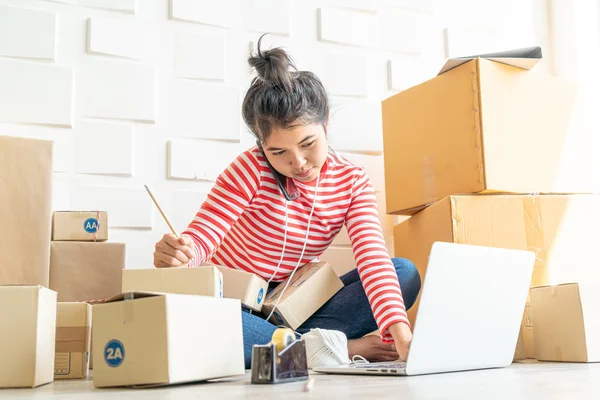 Asya kadın iş sahibi çalışan evde ambalaj kutusu ile w