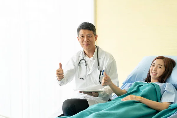 Asiático médico sênior sentado na cama do hospital e discutir com — Fotografia de Stock