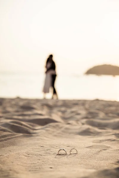 Ringe am Strand mit Braut und Bräutigam im Hintergrund — Stockfoto