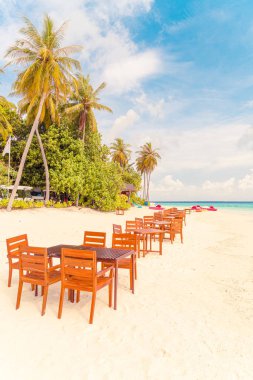 Maldiv 'de deniz manzaralı arka plan ile sahilde ahşap masa ve sandalye
