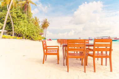 Maldiv 'de deniz manzaralı arka plan ile sahilde ahşap masa ve sandalye