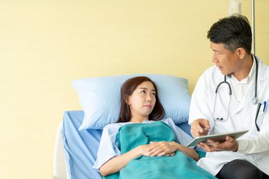 Hastane yatağı üzerinde oturan ve ile tartışırken Asya kıdemli doktor 