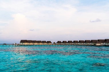 Su bungal ile Maldivler Adası üzerinde güzel tropikal günbatımı