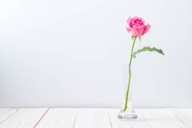 Ahşap arka plan üzerinde cam vazo içinde pembe Gül