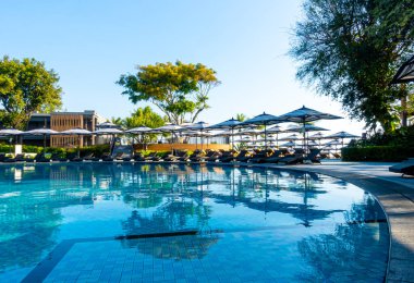 Güzel lüks şemsiye ve sandalye otel ve tatil konsepti için mavi gökyüzü ile yüzme havuzu etrafında etrafında