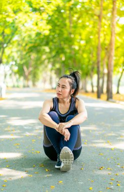 Parktaki egzersizden sonra Asyalı kadın oturuyor ve dinleniyor.