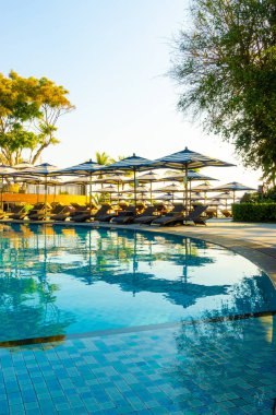 Güzel lüks şemsiye ve sandalye otel ve tatil konsepti için mavi gökyüzü ile yüzme havuzu etrafında etrafında