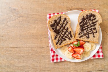 Kahvaltıda taze muz, çilek ve çikolatalı tam buğday ekmeği.