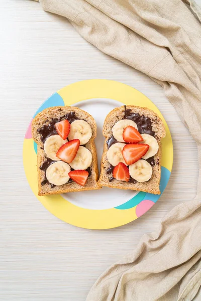 whole wheat bread toasted with fresh banana, strawberry and chocolate for breakfast