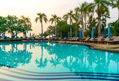 Gün batımında yüzme havuzunda şemsiyeli plaj sandalyesi ya da bilardo yatağı