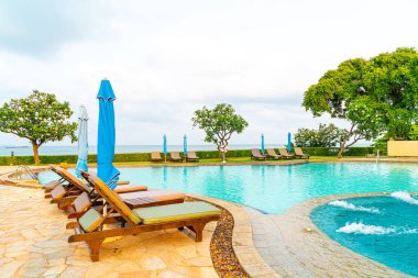 Tayland 'da Pattaya' da deniz plajı geçmişi olan havuz etrafında havuz ve şemsiye.