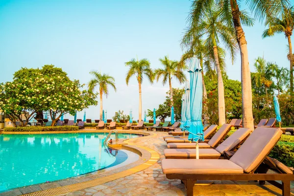 Hindistan cevizi palmiyeli havuz etrafında sandalye ve şemsiye - tatiller ve tatil kavramı