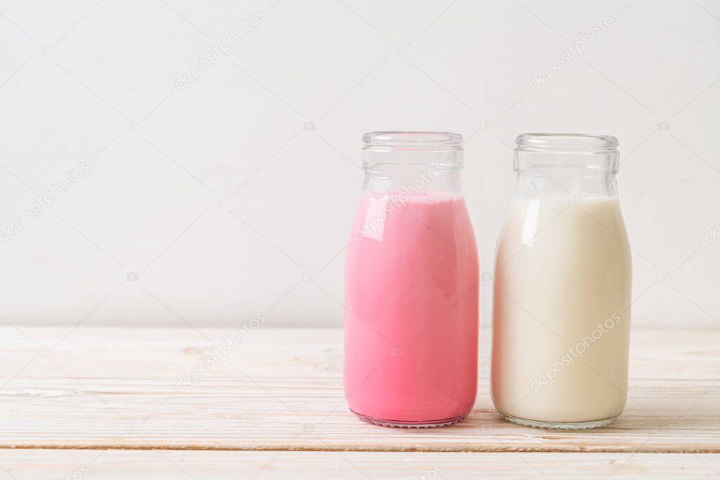 pink milk or strawberry milk with fresh milk in bottle on wood background