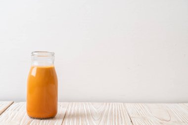 Tahta arka planda, şişede Tayland sütü çayı.