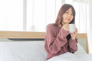Güzel Asyalı kadınlar sabahları yatakta kahve içerler.
