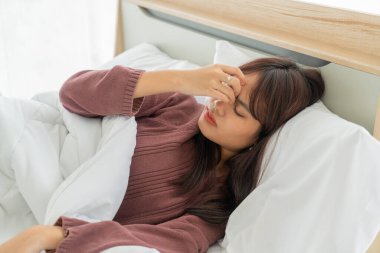 Güzel Asyalı kadınların baş ağrısı ve yatakta uyuması.