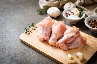 Taze çiğ tavuk kanatları (drumette veya baget çubuğu) ahşap tahtada malzemelerle birlikte.