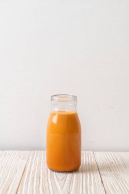 Tahta arka planda, şişede Tayland sütü çayı.