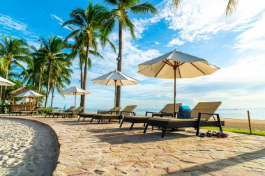 Otelde açık havuzda güzel bir şemsiye ve sandalye ve gün batımında hindistan cevizi palmiyesi ağacı olan bir tatil ve tatil konsepti.