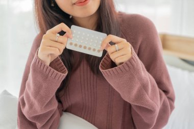 Güzel Asyalı kadınlar ellerinde doğum kontrol hapı tutuyor.