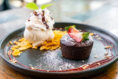 Çilekli çikolatalı lav ve siyah tabakta vanilyalı dondurma.